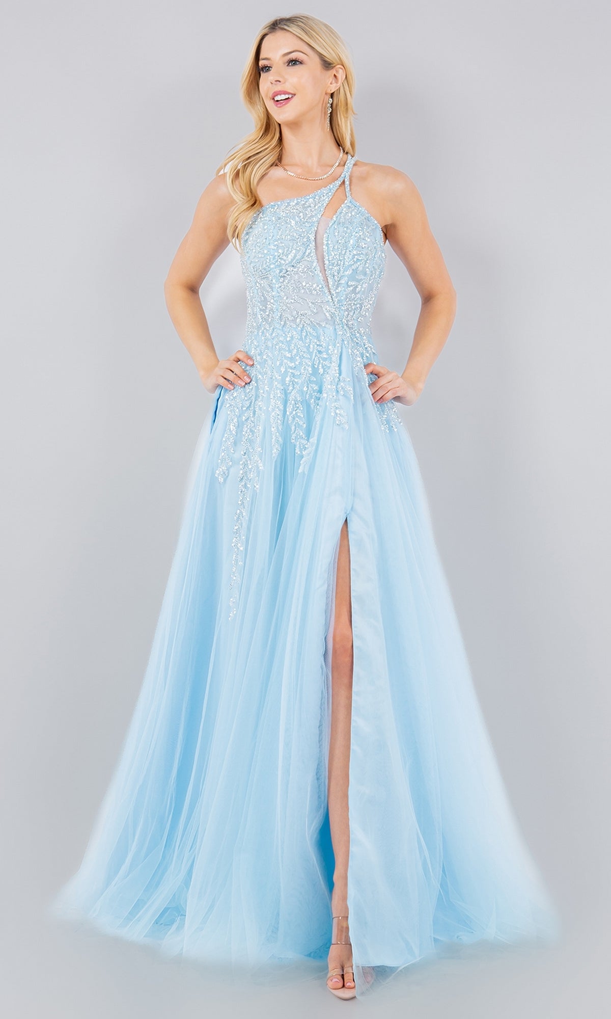 A woman stands elegantly against a plain background in the Cinderella Couture 8118J pastel tulle prom dress, a light blue, floor-length one-shoulder gown with sequin vine print details and a high slit.